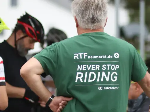 Männer in Radlerkleidung, einer trägt ein grünes T-Shirt mit der Aufschrift "RTFneumarkt.de NEVER STOP RIDING".