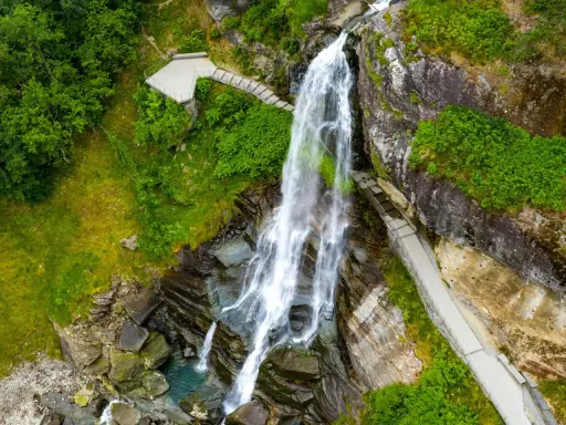 Majestätischer norwegischer Wasserfall stürzt in ein türkisfarbenes Becken. Wege führen Besucher nah heran.