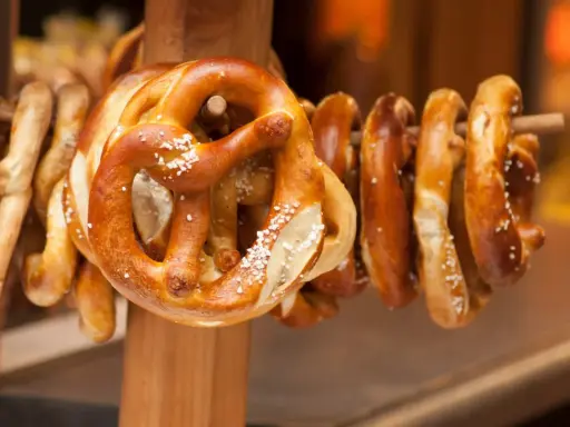 Des bretzels dorés, saupoudrés de gros sel, sont suspendus sur un support en bois. Ces spécialités lorraines invitent à la dégustation.