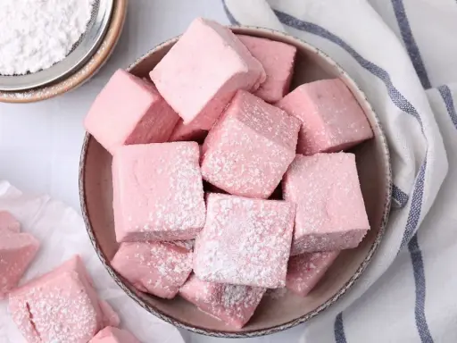 Dulces cubos rosados, como se hacen las nubes de azúcar, espolvoreados con azúcar glas.