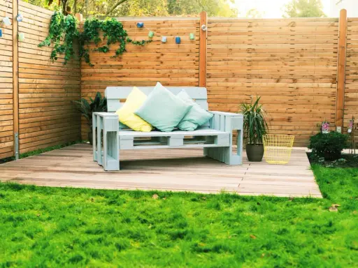Ein gemütliches Palettensofa bauen: Ein hellblaues Sofa aus Paletten mit Kissen steht auf einer Holzterrasse im Garten.