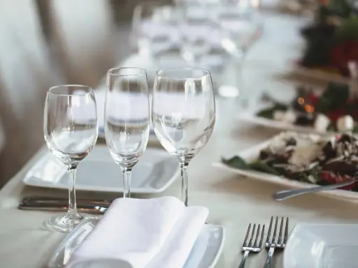 Trois verres à eau sont disposés sur une table dressée, prêts pour un repas.