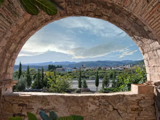 Vista de un pueblo desde un arco de ladrillo. Un paisaje con montañas y vegetación, ideal para ver en altura.