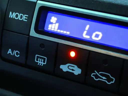 El aire acondicionado del coche muestra "Lo" indicando baja temperatura. El ventilador está al mínimo y la luz roja está encendida.