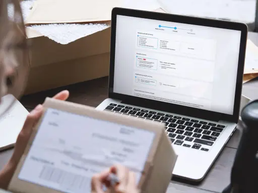Osoba przygotowuje zwrot kurierem, wypełniając formularz na laptopie. Na ekranie widoczne są dane nadawcy i odbiorcy.