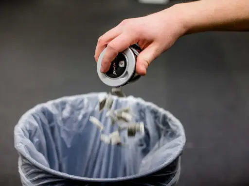 En hand tömmer snusdosan i en papperskorg. Ett steg för att sluta snusa.