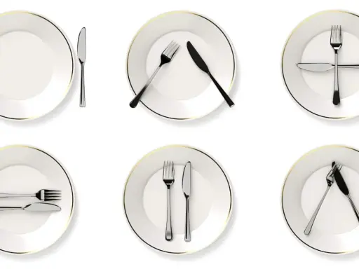 Six assiettes blanches avec des couverts disposés de différentes manières, illustrant la position des couverts signification.