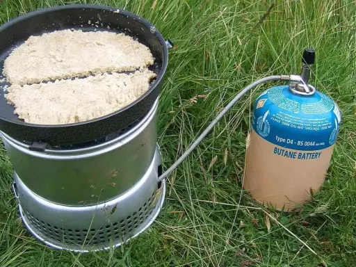 Två plättar steks i en stekpanna på en campingkök. Ett perfekt friluftsmat recept för äventyret.