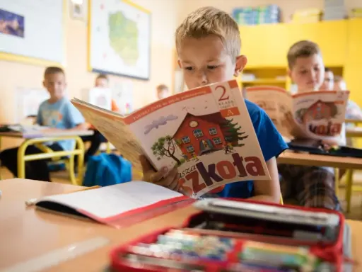 Chłopiec z zapałem czyta podręcznik "Nasza Szkoła". To dobry start dla każdego ucznia, by z radością poznawać świat.