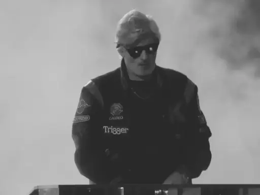 Młody artysta w okularach przeciwsłonecznych, w kurtce z naszywkami, gotowy do występu. Jego styl to czysty ras hip-hop.