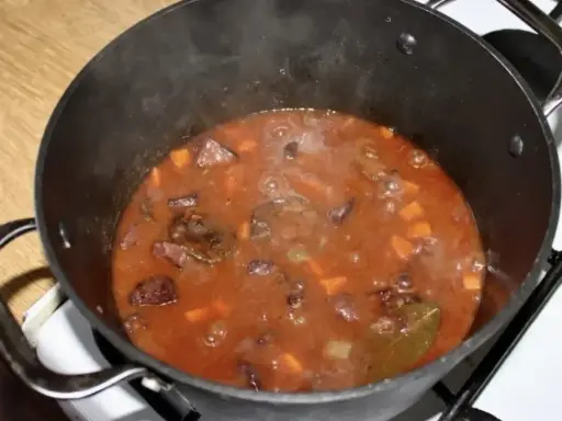 Gorący gulasz z dzika po myśliwsku bulgocze w garnku. Aromatyczny sos z kawałkami mięsa i warzyw.