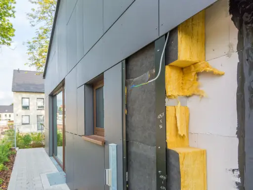 Fassade im Bau: WDVS selber machen mit gelber Steinwolle-Dämmung, die an einer grauen Verkleidung angebracht wird.