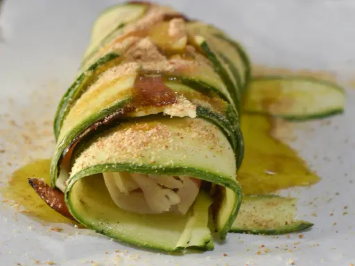 Delizioso rotolo di zucchine, avvolto con cura e cosparso di pangrattato e olio d'oliva. Un piatto leggero e gustoso.