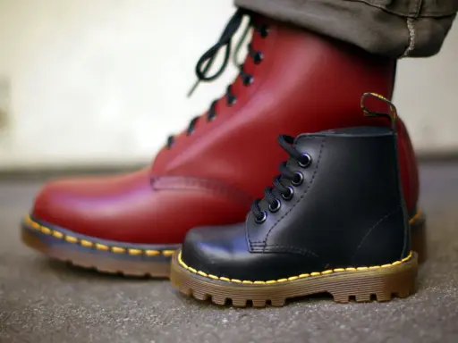 Zwei Dr. Martens Stiefel, ein roter und ein schwarzer, zeigen die Qualität des Dr. Martens Leder.
