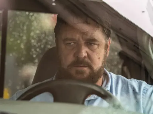 Russell Crowe bakom ratten i en bil, med regndroppar på vindrutan. En intensiv scen från filmer med Russell Crowe.