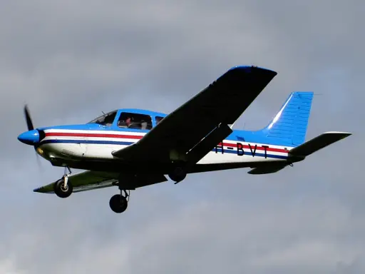 Blau-weiße Piper PA mit roten Streifen fliegt im Himmel.
