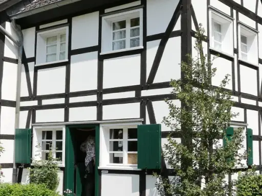Ein liebevoll saniertes Fachwerkhaus mit grünen Fensterläden und üppiger Bepflanzung.