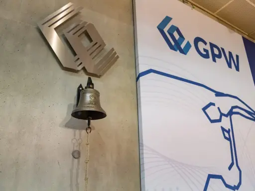 Dzwonek giełdowy GPW, symbolizujący rozpoczęcie obrotu, obok logo giełdy.