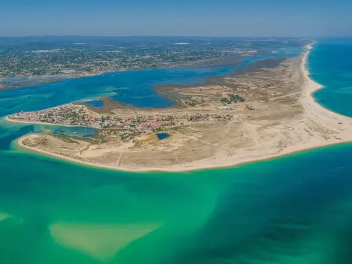 Luftaufnahme der Faro Inseln mit türkisfarbenem Wasser, Sandstränden und einer kleinen Stadt.
