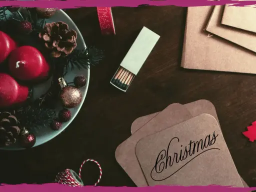 Candele rosse, pigne e decorazioni natalizie su un tavolo scuro, pronte per scrivere una poesia di Natale per adulti.