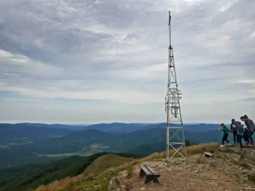 Grupa turystów podziwia widok na góry z wieżą telekomunikacyjną. Smerek z Wetliny wita wędrowców.