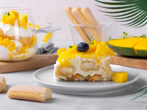 Un délicieux tiramisu mangue, garni de fruits frais et de biscuits à la cuillère. Une touche tropicale pour un dessert rafraîchissant.
