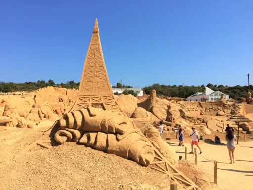 Beeindruckende Sandskulpturen, darunter der Eiffelturm, im Sand City Algarve. Besucher bestaunen die Kunstwerke.
