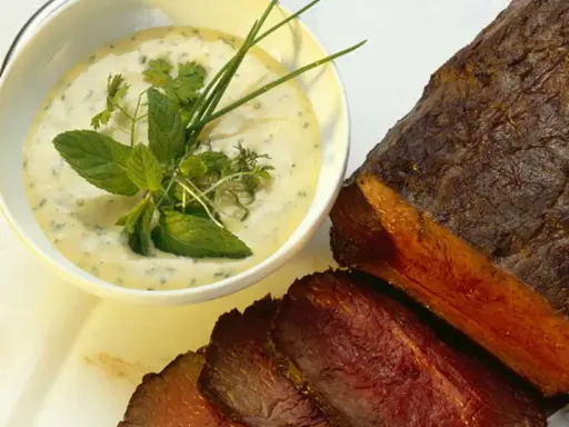 Sauce crémeuse aux herbes pour accompagner un rôti de bœuf juteux, garnie de menthe fraîche et de ciboulette.