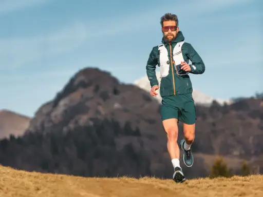 Ein Mann läuft in den Bergen, was ist ein ultramarathon? Er trägt Laufkleidung und eine Weste.