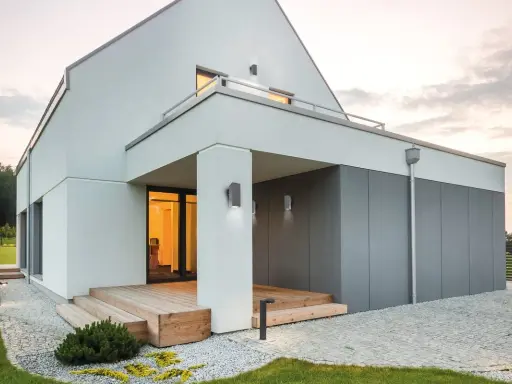 Nowoczesne oświetlenie elewacji podkreśla architekturę domu. Lampy ścienne i stojące tworzą przytulną atmosferę.