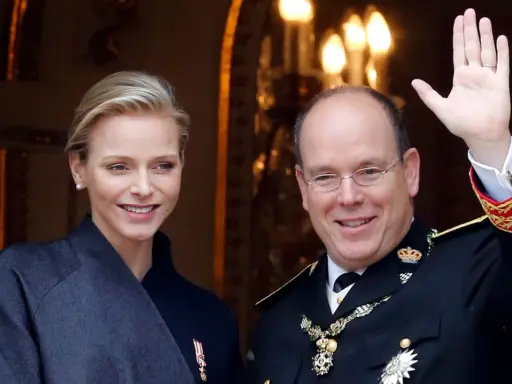 Charlene, furstinna av Monaco, ler vid sidan av prins Albert. Han vinkar glatt till publiken.