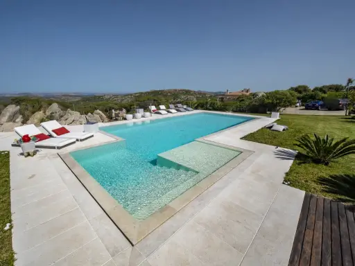 Lussuosa piscina in Sardegna, con vista mare e colline. Ideale per rilassarsi dopo un viaggio in traghetto.