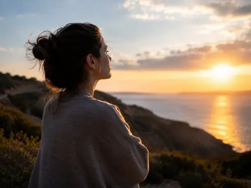 Frau blickt nachdenklich auf Sonnenuntergang über dem Meer. Die Weite spiegelt ihre **Angst vor Kontrollverlust** wider, während sie nach innerem Frieden sucht.