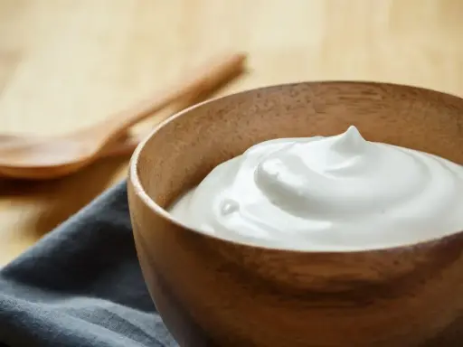Una ciotola di legno contiene una soffice crema al latte, pronta per essere gustata.