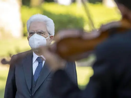 Un uomo con mascherina bianca ascolta un violinista. Un bel tacer non fu mai scritto, ma la musica parla.
