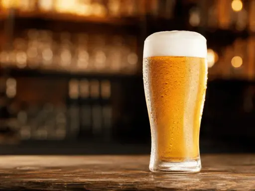 Schłodzony pilsner z obfitą pianką na blacie drewnianego baru.