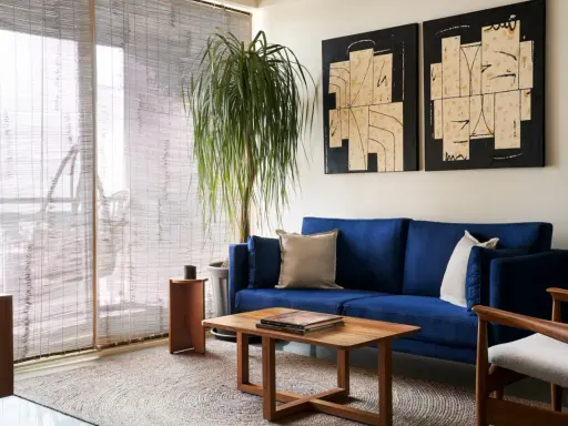 Salones muy pequeños con encanto: sofá azul vibrante, mesa de centro de madera, planta frondosa y arte abstracto en las paredes.