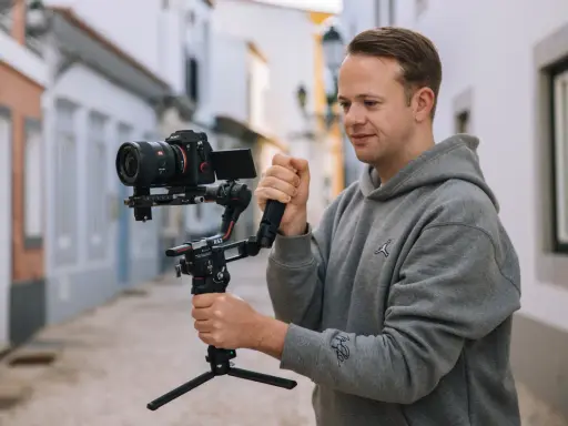 Mężczyzna trzyma profesjonalny aparat do nagrywania na stabilizatorze, gotowy do uchwycenia dynamicznych ujęć na ulicy.