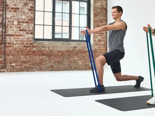 Mann und Frau machen Ausfallschritte mit Widerstandsbändern. Effektives HIIT Training für zu Hause.