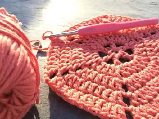 Koralowa włóczka i szydełko tworzą wzór. Powstaje piękny, ażurowy crochet pattern.