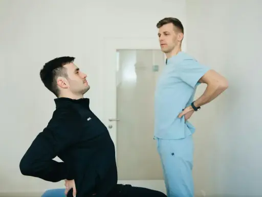 Fizjoterapeuta pomaga pacjentowi z chorobą Scheuermana w ćwiczeniach poprawiających postawę.