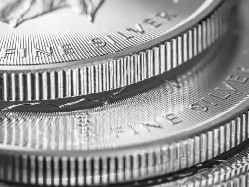 Zbliżenie na stos monet z napisem "FINE SILVER". Błyszczące srebro, idealne na prognozy inwestycyjne.