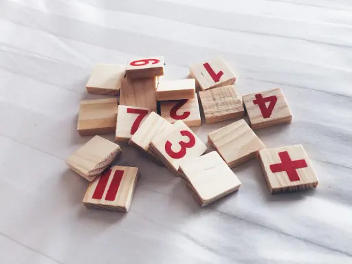 Drewniane klocki z cyframi 1, 2, 3, 4, 6, 7, 11 i znakiem plus. Jak wyliczyć numerologię?