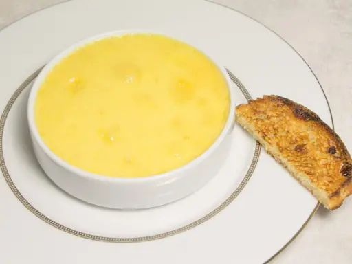 Crème onctueuse à la noix de coco, servie dans un bol blanc avec une tranche de pain grillé.