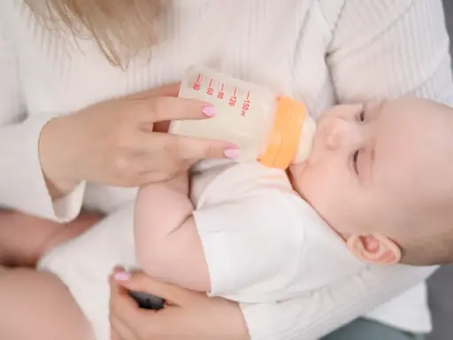 Mama karmi dziecko butelką. Choć mleko Bebilon wycofane, maluch spokojnie pije.