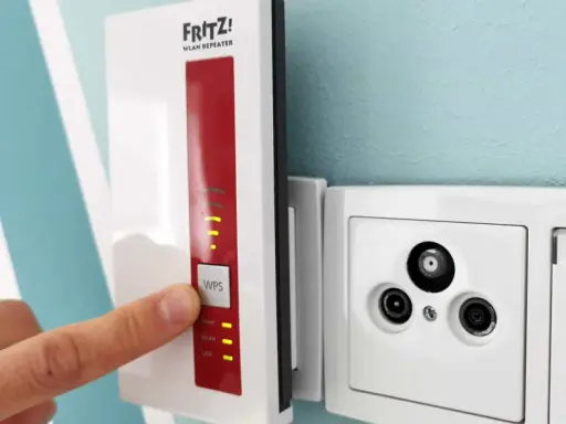 Fritz! WLAN Repeater verbessert das Signal, um **WLAN durch Betondecke** zu leiten. Ein Finger drückt auf die WPS-Taste.