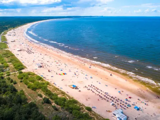 Słoneczne plaże w Polsce tętnią życiem. Tłumy ludzi odpoczywają na piaszczystym brzegu, kąpią się w morzu i cieszą się wakacjami.
