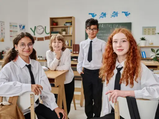 Vier Schüler in weißem Hemd und schwarzer Krawatte im Klassenzimmer. Ein Vergleich des Schulsystems Finnland und Deutschland könnte hier beginnen.