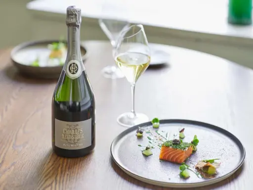Flasche Charles Heidsieck Champagner neben Lachs mit Kaviar auf einem Teller.