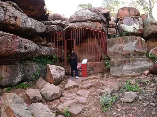 Persona observa pinturas rupestres albarracín, protegidas por una valla roja.